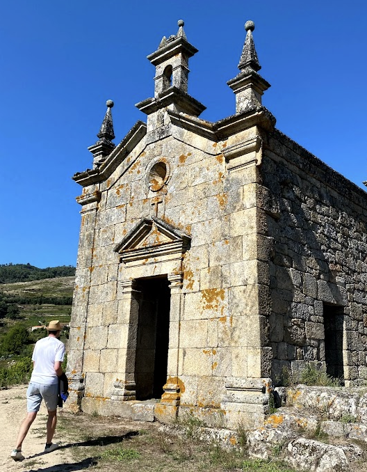 A man walks towards a historic small stone building